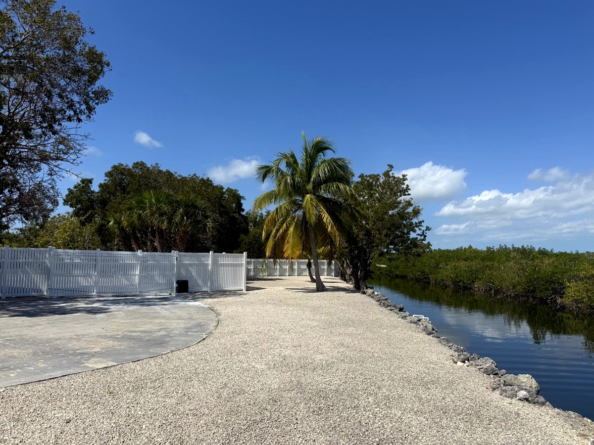 Private gated driveway with canal and palm trees